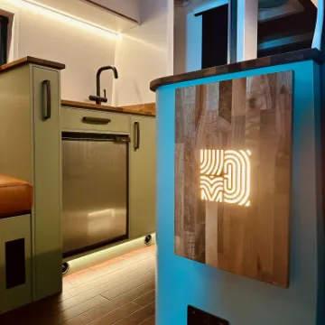 A bar interior with the looping monogram lit up on a wooden panel