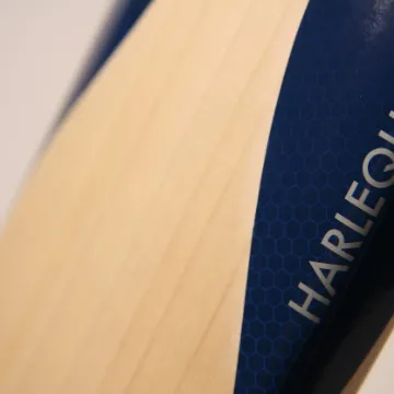 Close-up of a cricket bat shoulder with the Harlequin name stamped into the wood