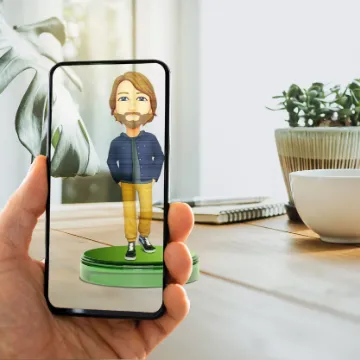 A phone held up in a living room, showing a cartoon avatar of a bearded man