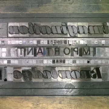 Metal letterpress type locked in a chase, reading “imagination is more important”