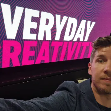Olly Whitman in front of a large pink screen reading “Everyday creativity”