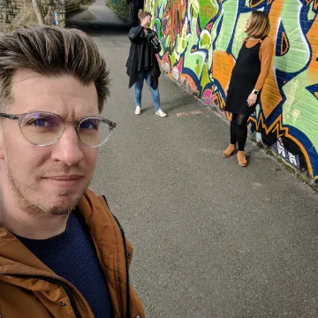 Olly Whitman in front of a graffiti-covered wall