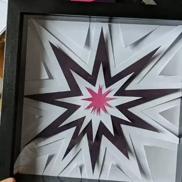 Hands holding a framed paper starburst in purple and pink, under a note reading “One down, four to go.”