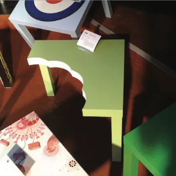A dark still life of green geometric shapes and scattered paper on a desk